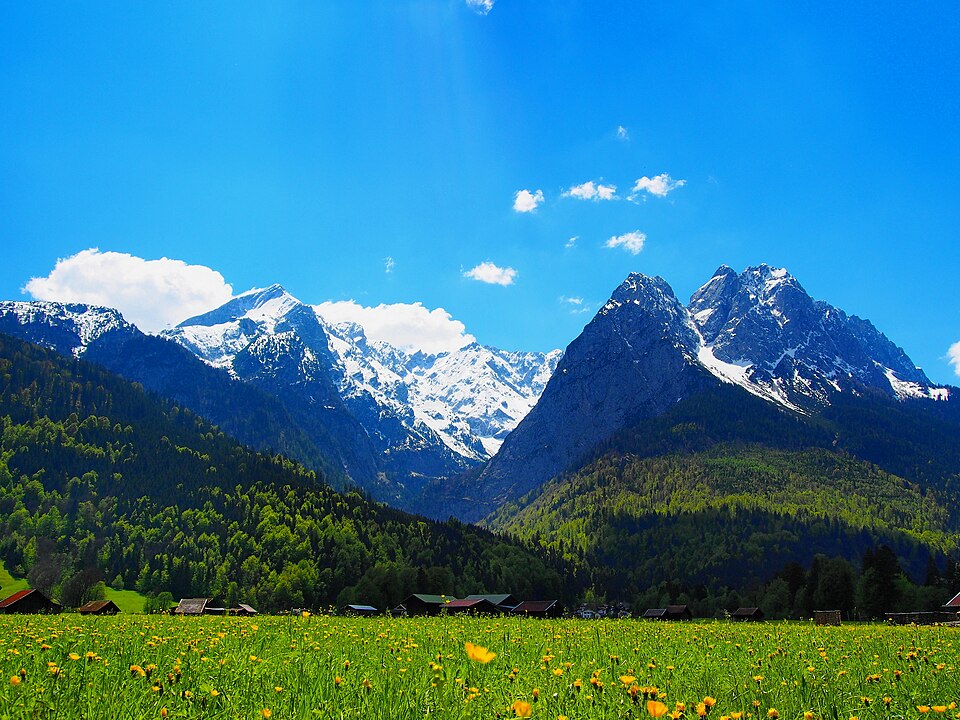 Les sommets encore enneigés du massif de la Zugspitze au-dessus des prairies alpines.